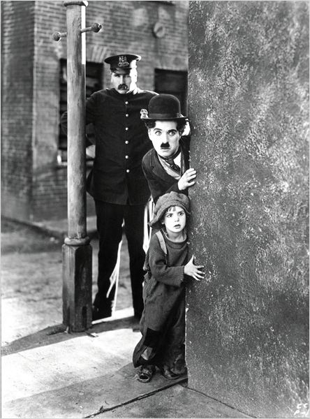 CHARLES CHAPLIN,  JACKIE COOGAN (niño) Y TOM WILSON (policía) EN "THE KID" (1921).